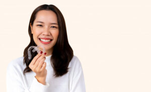 beautiful-asian-woman-smiling-with-hand-holding-dental-aligner-retainer-invisible