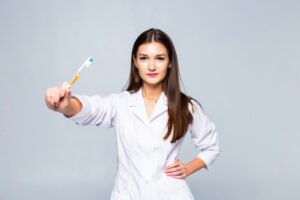 smiling-woman-medic-with-braces-with-great-teeth-holding-tooth-brush-isolated-white-wall_