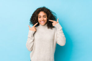 young-african-american-curly-hair-woman-smiles-pointing-fingers-mouth